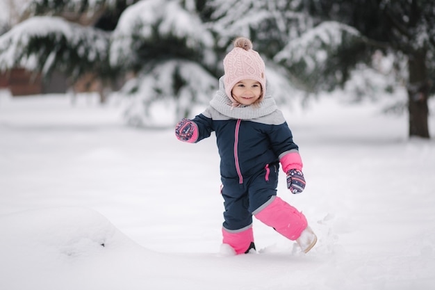 Bambina felice che cammina nel parco sulla neve