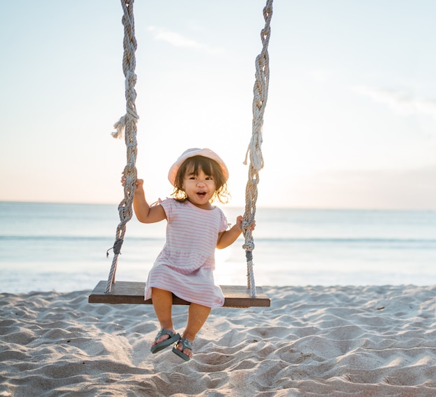 Bambina felice che dondola in spiaggia