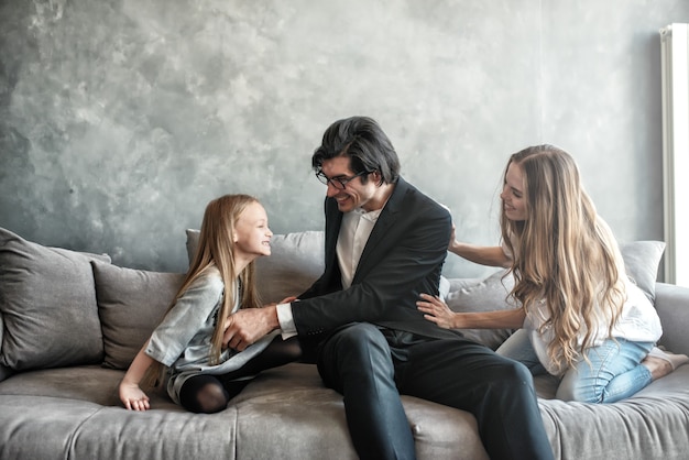 Bambina felice che gioca con sua madre e suo padre sul divano