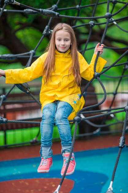 Bambina felice che gioca sul campo da giuoco all'aperto nel giorno di autunno