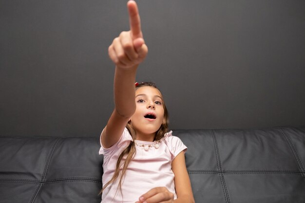 Bambina felice che guarda TV nella notte che si siede su uno strato nel salone a casa