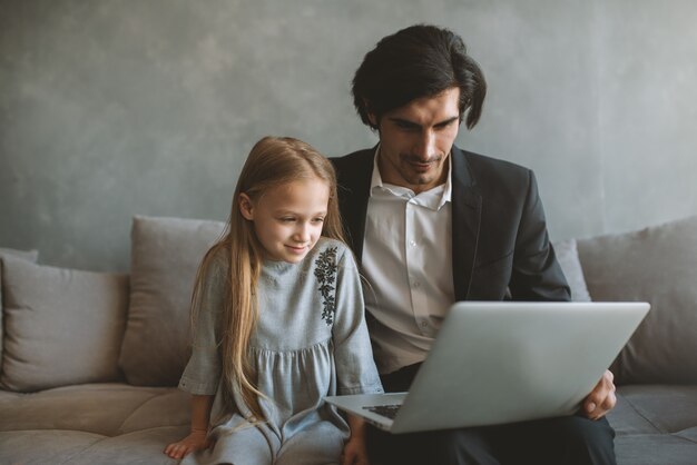 Bambina felice che guarda un film sul computer con suo padre a casa