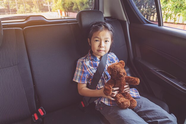 Bambina felice che indossa le cinture di sicurezza in auto