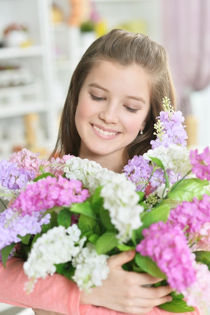 Bambina felice che posa a casa con i fiori