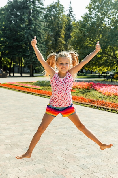 Bambina felice che salta nel parco. bambina che mangia il gelato e si diverte in città.