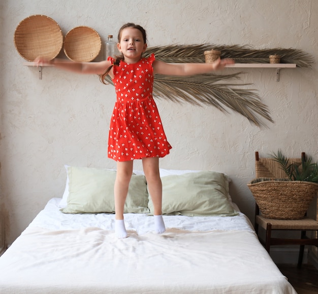 Bambina felice che salta sul letto, cantando una canzone.