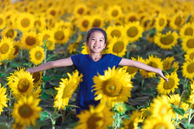 Bambina felice che sente l&#39;odore di un girasole sul campo