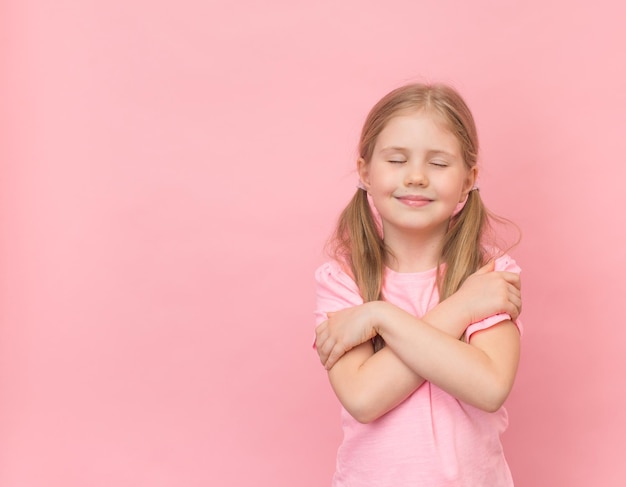 Bambina felice che si abbraccia su sfondo rosa con spazio per la copia Mi amo consept