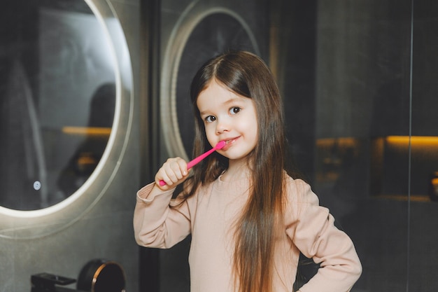 Bambina felice che si lava i denti davanti allo specchio del bagno Igiene mattutina