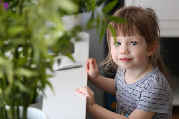 Bambina felice che si siede alla tavola che esamina