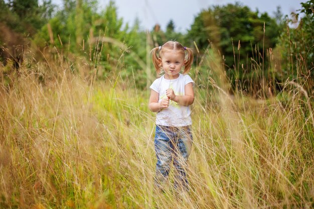 Bambina felice che sorride all'aperto. Bella giovane neonata che riposa sul campo estivo