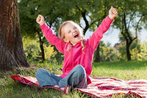 Bambina felice con le mani in alto nel parco estivo