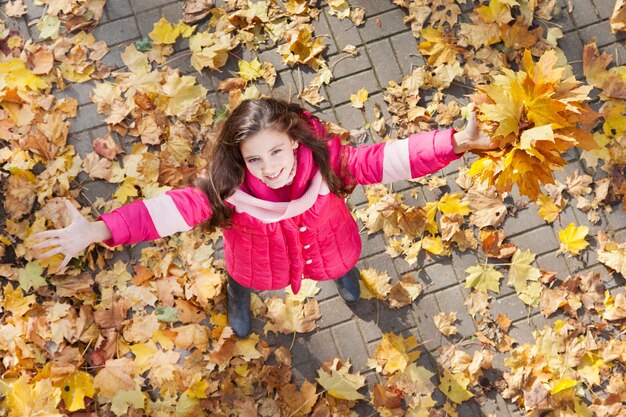 Bambina felice con le mani in alto nella vista dall'alto del parco autunnale