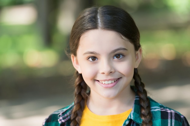 Bambina felice con un sorriso adorabile sulla pelle sana del viso giovane estate all'aperto, cura della pelle.