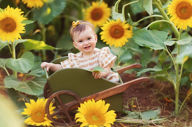 Bambina felice divertendosi tra i girasoli fioriti sotto i dolci raggi del sole in un carrello