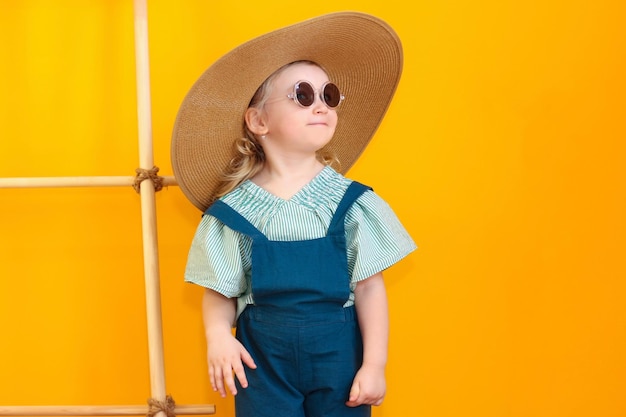 Bambina felice il bambino si sta godendo l'estate Presto in vacanza e sta facendo i bagagli per un viaggio Prova occhiali da sole, un cappello e beve succo