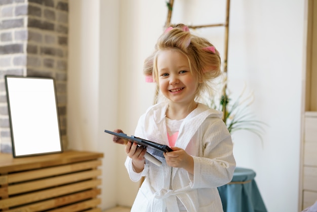 Bambina felice in bigodini che tengono trucco