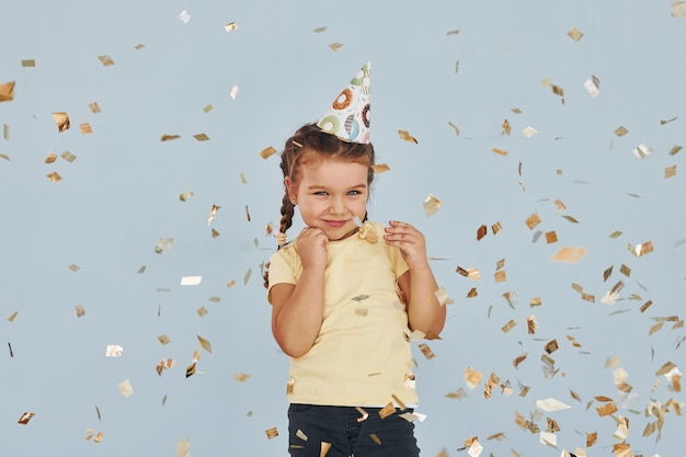 Bambina felice in piedi e divertirsi al chiuso alla festa di compleanno