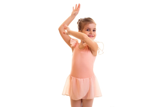 Bambina felice in vestito rosa che balla su priorità bassa bianca in studio