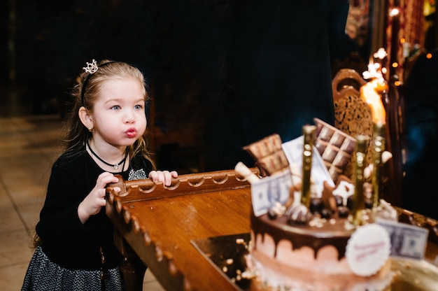 Bambina felice, soffiando le candeline sulla torta di festa.