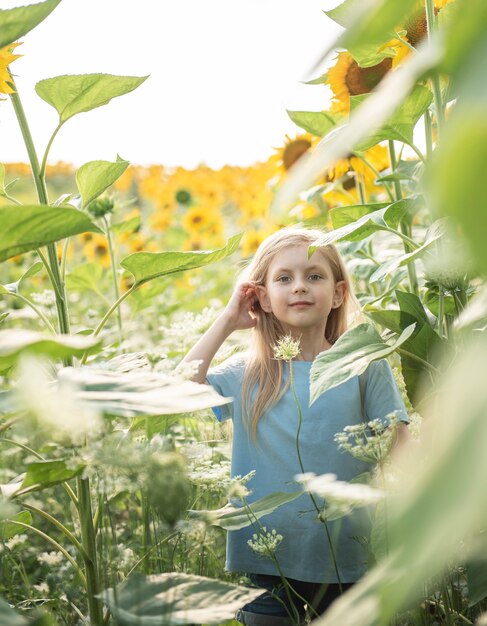 Bambina felice sul campo di girasoli in estate.