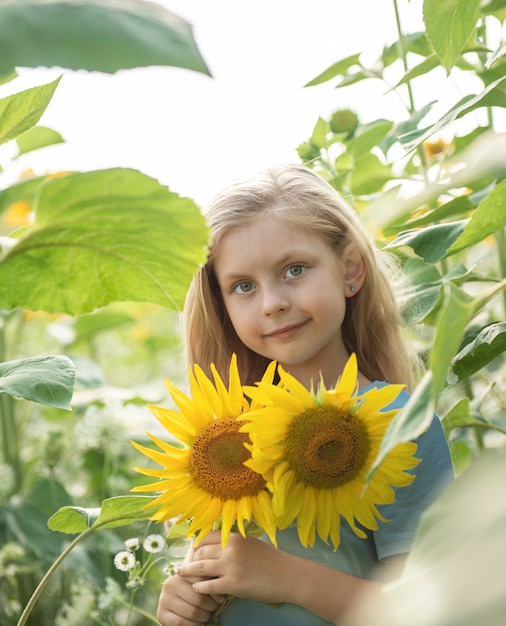 Bambina felice sul campo di girasoli in estate.