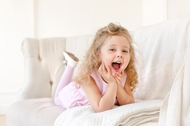 Bambina felice sul sofà bianco