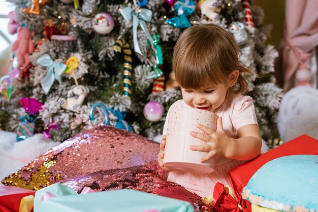 Bambina felice sullo sfondo dell'albero di Natale che gioca