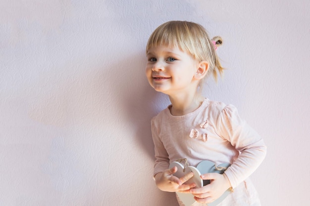 Bambina felice Una bambina con i capelli biondi tiene in mano due cuori bianchi di legno