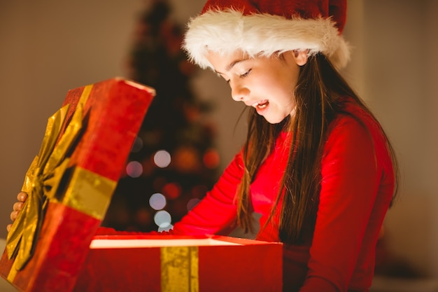 Bambina festiva che apre un regalo di natale d&#39;ardore