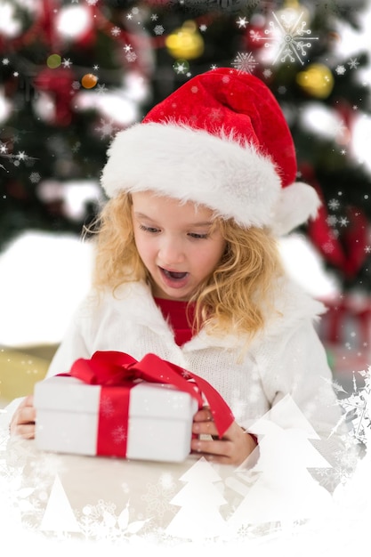 Bambina festiva che esamina regalo contro la caduta della neve