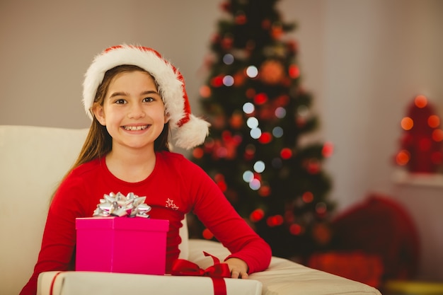 Bambina festiva che sorride alla macchina fotografica con i regali