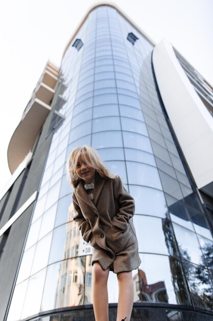 Bambina fresca ed elegante con i capelli bianchi sullo sfondo di un edificio di vetro in città