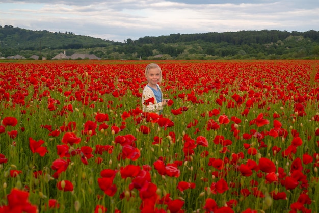 Bambina gioca all'aperto nel campo di papaveri adorabile bambino su sfondo di papaveri bambini vicino al fiore di primavera