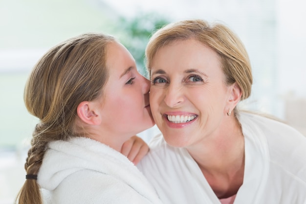 Bambina graziosa che bacia sua madre sulla guancia