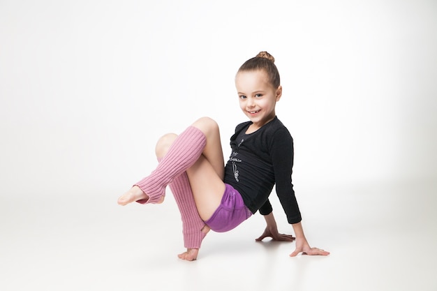 Bambina graziosa che fa ginnastica sopra fondo bianco