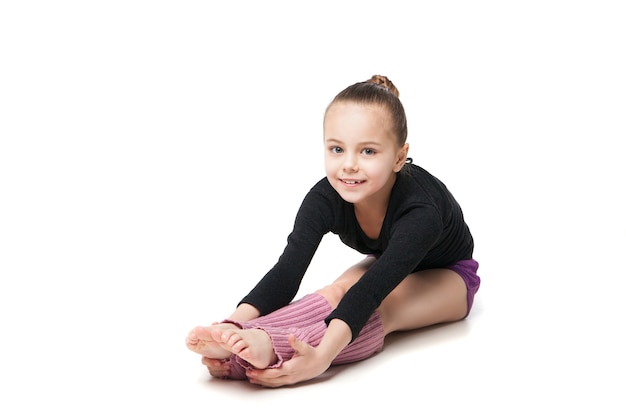 Bambina graziosa che fa ginnastica sopra fondo bianco