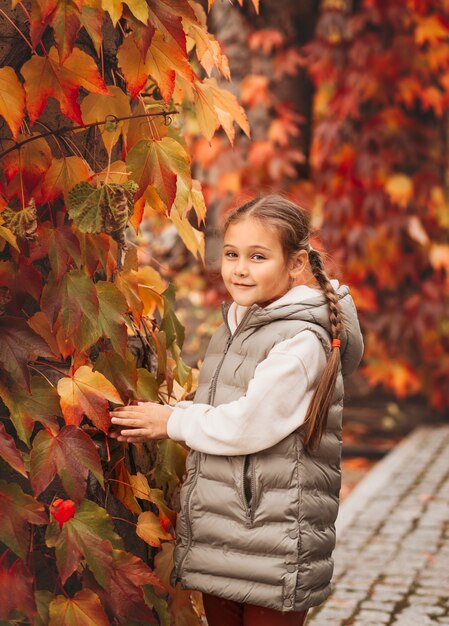 Bambina graziosa che riposa nel parco autunnale