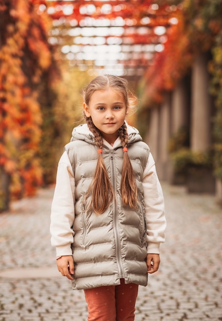 Bambina graziosa che riposa nel parco autunnale