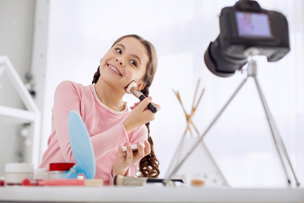 Bambina graziosa che si comporta come una truccatrice davanti alla telecamera