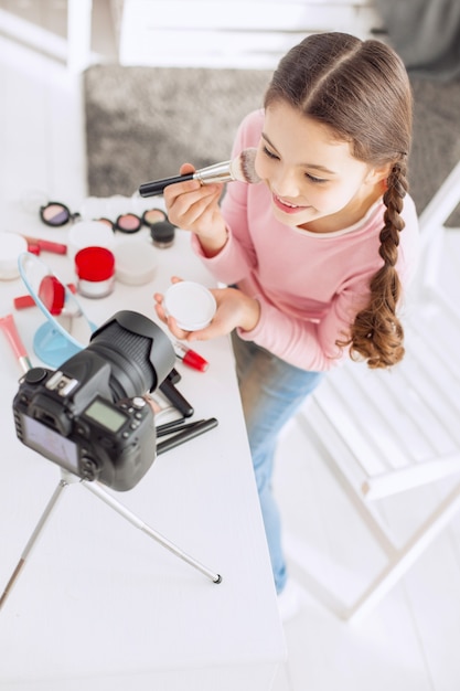 Bambina graziosa che si comporta come una truccatrice davanti alla telecamera