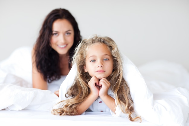 Bambina graziosa con capelli biondi che si trovano sul letto