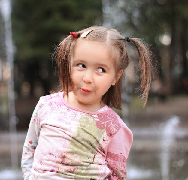 Bambina graziosa sullo sfondo della fontana della città.