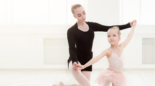 Bambina guardando ballerino professionista. Bambino carino che sogna di diventare ballerina, copia spazio. Sfondo della scuola di danza classica, pratica per i bambini