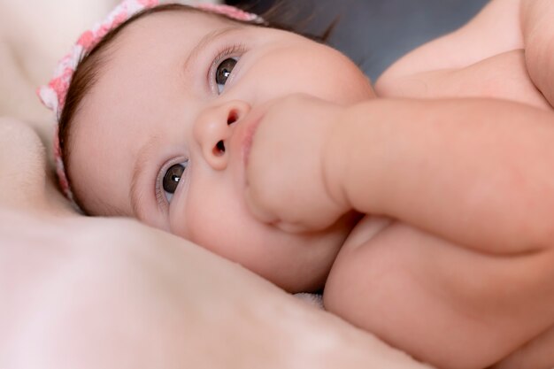 Bambina, guardando la telecamera e mettendo la mano in bocca