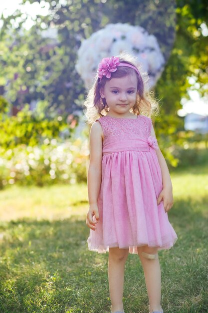bambina in abito rosa che si diverte in giardino