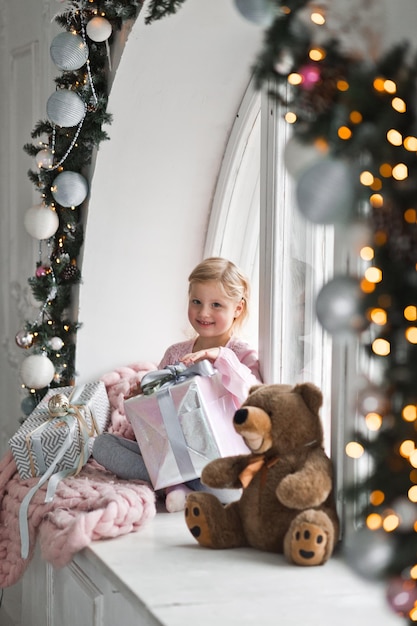 Bambina in abito rosa con enorme regalo di Natale 2088