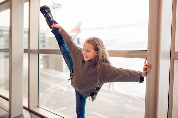 Bambina in aeroporto vicino alla grande finestra mentre aspettano l'imbarco