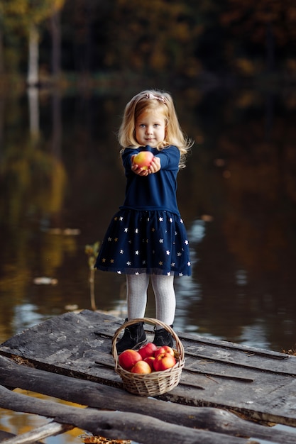 Bambina in autunno con un cesto di mele.