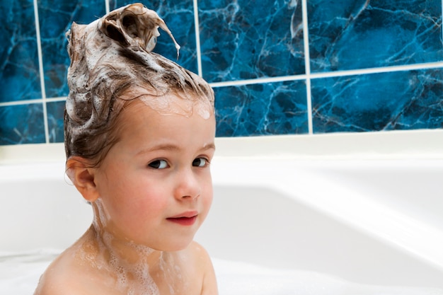 Bambina in bagno che lava i suoi capelli. Il simbolo dell'educazione alla purezza e all'igiene.